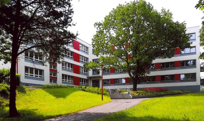 Auf einem weitläufigen Gelände befindet sich ein viergeschössiges, modernes Schulgebäude .