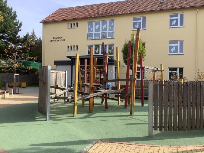 Spielplatz auf dem Schulhof mit Eingangsbereich im Hintergrund