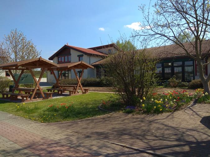 Blick auf den Schulgarten. Dahinter Klassenräume. Links das grüne Klassenzimmer.