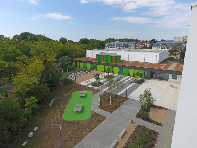 Sporthalle mit Schulhof. Es handelt sich um eine Dreifelderhalle.